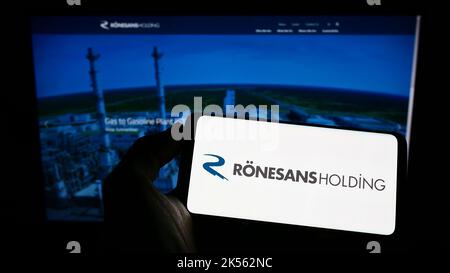 Person, die Mobiltelefon mit dem Logo des türkischen Konglomerats Ronesans Holding auf dem Bildschirm vor der Business-Webseite hält. Konzentrieren Sie sich auf die Telefonanzeige. Stockfoto