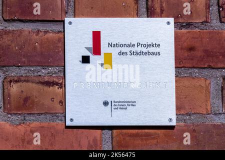 06. Oktober 2022, Mecklenburg-Vorpommern, Gadebusch: Ein Metallschild informiert über das Prämienprojekt bei den Nationalen Projekten Stadtentwicklung des ehemaligen Bundesministeriums des Innern, für Bau und Heimat. Die renovierte Südfassade des Renaissanceschlosses von Gadebusch wird feierlich übergeben. Das Schloss soll künftig die Staatliche Musikakademie beherbergen. Die Revitalisierung des Schlosskomplexes durch die Initiative „Zukunft Schloss Gadebusch“ kostete 650.000 Euro. Das Gebäudeensemble, ein seltenes Beispiel der Mecklenburger Backsteinrenaissance, wird weiterhin als genutzt Stockfoto