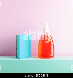 Ästhetische bunte quadratische Schale Waschkomposition mit Reinigungsschwamm und Seife in einer Flasche, die auf einem Podium vor rosa Hintergrund steht. Stockfoto