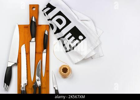 Ein Satz hochwertiger Küchenmesser auf einem Schneidbrett. Verschiedene Küchenmesser auf Holzschneidebrett legen, flach legen, Blick von oben, Platz für ein Stockfoto