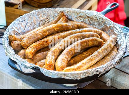 Saftig appetitlich gegrillte Würstchen in einer Pfanne in Folie aus nächster Nähe Stockfoto