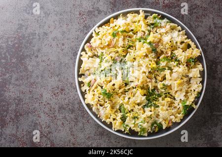 Köstliche, duftende Mafalda-Pasta mit wilder Rucola, knusprigen Pistazien, Parmesankäse und Zitronenschale aus nächster Nähe auf einem Teller auf dem Tisch Stockfoto