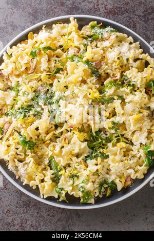 Sizilianische Mafalda Corta Pasta di Gragnano mit Zitrone, gerösteten Pistazien und Wild Rocket Nahaufnahme in der Platte auf dem Tisch. Vertikale Draufsicht von oben Stockfoto