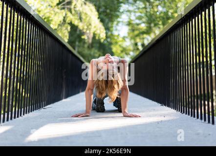 Athletische Pose eines attraktiven 22 Jahre blonden Mädchens auf einer Fußgängerbrücke, Belgien Stockfoto