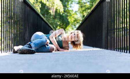 Athletische Pose eines attraktiven 22 Jahre blonden Mädchens auf einer Fußgängerbrücke, Belgien Stockfoto