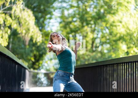 Athletische Pose eines attraktiven 22 Jahre blonden Mädchens auf einer Fußgängerbrücke, Belgien Stockfoto