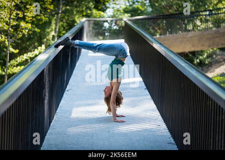 Athletische Pose eines attraktiven 22 Jahre blonden Mädchens auf einer Fußgängerbrücke, Belgien Stockfoto