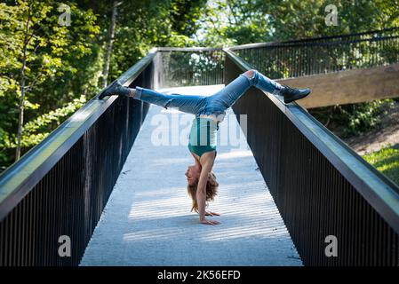 Athletische Pose eines attraktiven 22 Jahre blonden Mädchens auf einer Fußgängerbrücke, Belgien Stockfoto