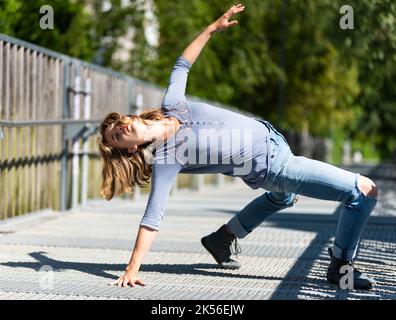 Athletische Pose eines attraktiven 22 Jahre blonden Mädchens auf einer Fußgängerbrücke, Belgien Stockfoto