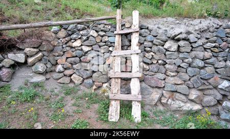 Holzleiter an der Gartenwand. Stockfoto