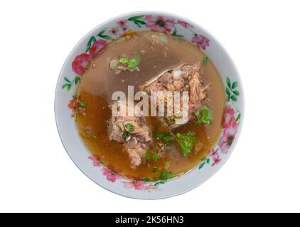 Schweinebrippsuppe oder Schweineknochensuppe mit Sojasauce und Pfeffer bestreut mit Koriander in Schüssel isoliert auf weißem Hintergrund mit Schneideweg. Stockfoto