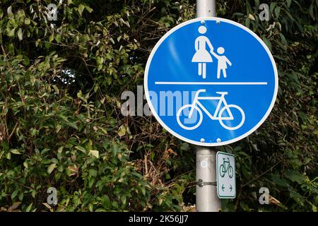 Deutscher Schild Bürgersteig Mit Radweg. Blauer Hintergrund Mit Fußgänger Und Fahrrad. Blaues Holländisches Verkehrsschild Mit Grünen Blättern. Straßenschild Pfad Für Stockfoto