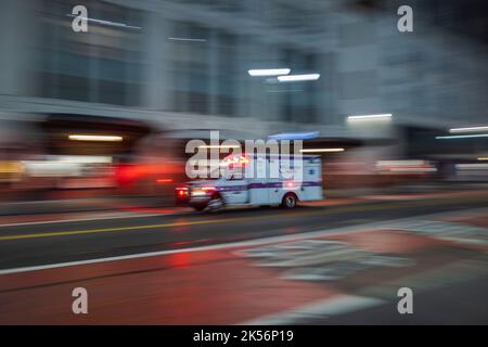 Schöner Blick auf die Straße mit Blick auf die Stadt bei Nacht. Racing Ambulance Auto auf der Vorderseite. New York. USA Stockfoto