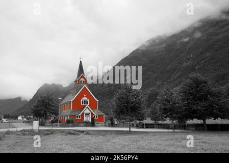 Alte 'Neue Kirche', erbaut 1934, Olden, Norwegen. Norwegen rote Kirche. Holzkirche. Umgeben von Bergen und niedrigen Wolken. Schwarzweißbearbeitung. Stockfoto