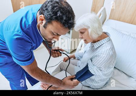 Der Arzt mit Stethoskop misst den Druck älterer Patientinnen mit Tonometer auf der Krankenhausstation. Prophylaxe und Behandlung der Hypertonie Stockfoto