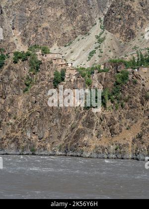 Abgelegenes afghanisches Dorf auf einer felsigen Klippe über dem Fluss Panj, von Darvaz, Gorno-Badakshan, in der Pamir-Bergregion Tadschikistans gesehen Stockfoto