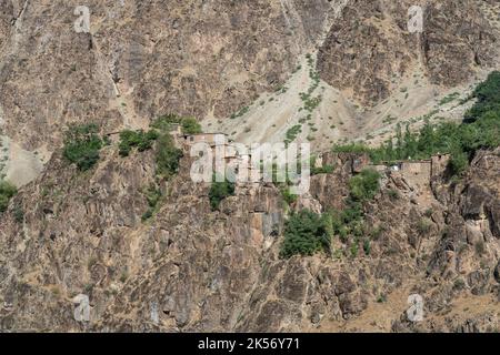 Isoliertes afghanisches Dorf auf felsigen Klippen über dem Fluss Panj, Darvaz, Gorno-Badakshan, Pamir-Bergregion von Tadschikistan Stockfoto