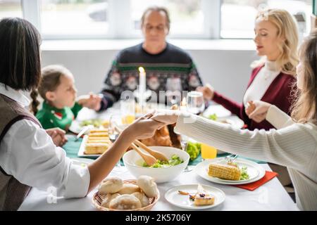 Interracial Familie mit geschlossenen Augen Hände halten und beten vor Danksageessen, Stock Bild Stockfoto