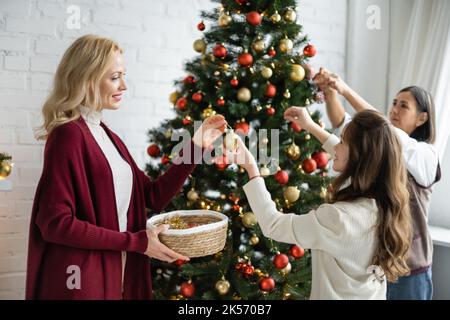 Teen Mädchen mit Mutter und multirassische Oma Dekoration weihnachtsbaum im Wohnzimmer, Stock Bild Stockfoto