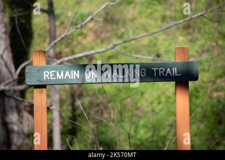 POVERTY POINT RESERVOIR STATE PARK, DELHI, LOUISIANA/USA – 05 2020. MÄRZ: Grünes Schild warnt Wanderer, auf dem Trail zu bleiben. Stockfoto