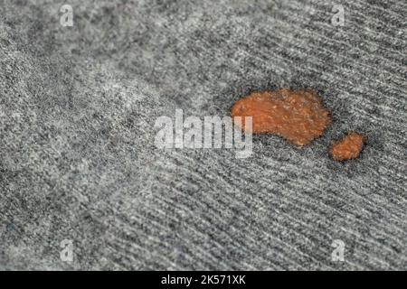 Getrocknete rote Tomatenfleck auf Kaschmir-Stoff, weicher Fokus aus nächster Nähe Stockfoto