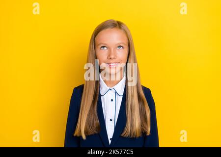 Foto von positiven niedlichen schönen Schulmädchen mit geraden Frisur tragen blauen Blazer suchen leeren Raum isoliert auf gelbem Hintergrund Stockfoto