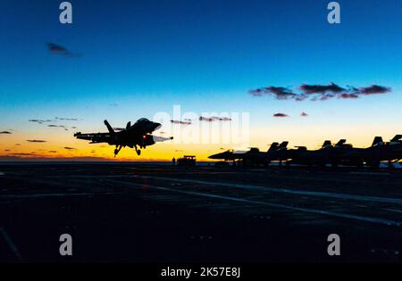 USS Ronald Reagan, Südkorea. 05. Oktober 2022. Ein F/A-18F Super Hornet Kampfflugzeug der US Navy, das an den Diamondbacks des Strike Fighter Squadron 102 befestigt ist, landet bei Sonnenuntergang auf dem Flugdeck des nuklearen Superträgers USS Ronald Reagan der Nimitz-Klasse während der Einsätze im Japanischen Meer am 5. Oktober 2022 in der Nähe von Südkorea. Kredit: MC2 Michael Jarmiolowski/US Navy Foto/Alamy Live Nachrichten Stockfoto