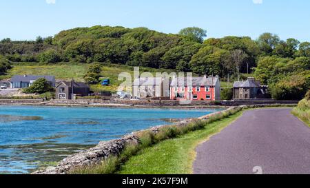 County Cork, Irland, 28. Mai 2022. Eine Bar und mehrere Häuser in einem irischen Küstendorf an einem sonnigen Tag. Kleines europäisches Dorf, Landschaft, Häuser in der Nähe Stockfoto