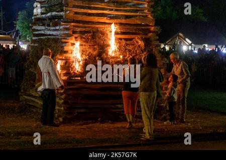 Frankreich, Eure, La Haye-de-Routot, traditionelles Lagerfeuer von Saint-Clair, eine 15 Meter hohe Pyramide aus trockenem Holz, wird auf dem Dorfplatz vor der Kirche und ihren tausendjährigen Eibungen errichtet. Eine Messe und ein Segen gehen der Verbrennung des Pfahls voraus, wenn das Kreuz an der Spitze nicht brennt, ist es ein gutes Zeichen für die kommenden 12 Monate, wenn ein verkohltes Holz, genannt brandon, nach Hause gebracht wird, wird das Haus vor Blitzschlag schützen Stockfoto