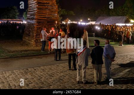 Frankreich, Eure, La Haye-de-Routot, traditionelles Lagerfeuer von Saint-Clair, eine 15 Meter hohe Pyramide aus trockenem Holz, wird auf dem Dorfplatz vor der Kirche und ihren tausendjährigen Eibungen errichtet. Eine Messe und ein Segen gehen der Verbrennung des Pfahls voraus, wenn das Kreuz an der Spitze nicht brennt, ist es ein gutes Zeichen für die kommenden 12 Monate, wenn ein verkohltes Holz, genannt brandon, nach Hause gebracht wird, wird das Haus vor Blitzschlag schützen Stockfoto