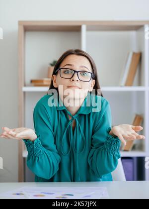 Ahnungsloses Achselzucken. Entschuldigung. Welche Geste auch immer. Verwirrt gleichgültig Geschäftsfrau Heben der Hände Schultern leider keine Idee tut mir leid bei der Büroarbeit Stockfoto