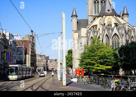 Menschen, die auf der Straße von Gent mit Hintergrund der St. Nikolaus-Kirche und Straßenbahnen Stockfoto