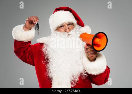 Vater weihnachten hält Lautsprecher und Autoschlüssel isoliert auf grauem, stockem Bild Stockfoto
