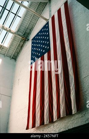 Eine riesige amerikanische Flagge hängt am Eingang des Salem (Armory) Visitor Centre im historischen Salem, Massachusetts. Stockfoto