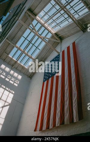 Eine riesige amerikanische Flagge hängt am Eingang des Salem (Armory) Visitor Centre im historischen Salem, Massachusetts. Stockfoto