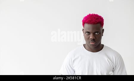 Wütender schwarzer Mann. Maskuline Kraft. Macht Stress. Negative Gedanken. Hintergrund der Werbung. Brutaler afrikanischer Kerl mit leuchtend rosa Haaren T-Shirt beim Betrachen Stockfoto