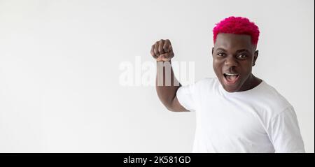Wütender Mann. Geste bedrohen. Kraft. Spannungsausbruch. Widerstrebige Gegner. Aggressiver afrikanischer Kerl mit rosafarbenem Haar, die Faust isoliert weiß Stockfoto