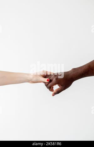 Multiethnische Liebe. Rassische Vielfalt. Gemischtes Paar. Frieden Harmonie. Unterstützung der Zusammenarbeit. Konzeptuelles Kunstportrait. Weiße weibliche und schwarze männliche Hände holdi Stockfoto