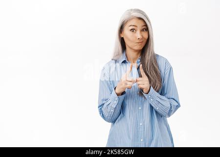 Bild von niedlichen asiatischen Frau suchen unschuldig und schüchtern, stehen über weißen Studio-Hintergrund Stockfoto