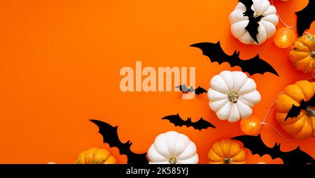 Halloween flach Lay Zusammensetzung aus schwarzem Papier Fledermäuse und Kürbisse auf orangefarbenem Hintergrund. Halloween-Konzept Stockfoto