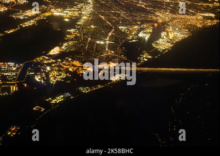 Fantastische Aussicht auf die Stadt bei Nacht, beleuchtet von goldenen Lichtern aus dem Fenster eines Flugzeugs, das hoch in den Nachthimmel fliegt. Abstraktion. Karte, Topog Stockfoto