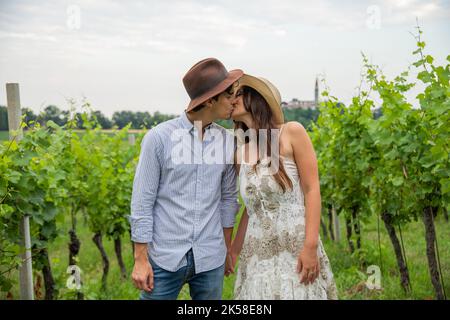 Junges Paar bei einem romantischen Spaziergang im Weinberg stoppen und küssen sich gegenseitig auf den Mund. Stockfoto