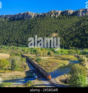 Zug über eine Brücke über den clark Fork River unter Klippen in der Nähe von drummond, montana Stockfoto