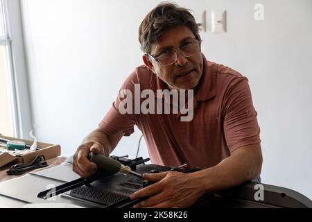 lateinischer Mann, der eine Basis für den Fernseher stellt, damit er an der Wand befestigt werden kann Stockfoto