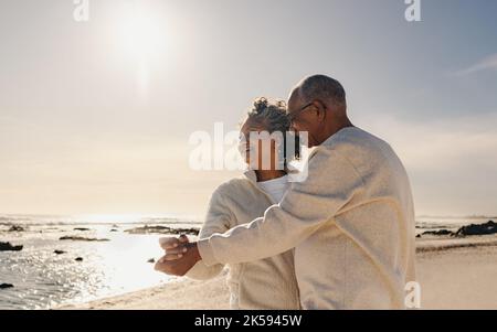 Glückliches Seniorenpaar, das lächelt, während es am Strand zusammen tanzt. Fröhliches, älteres Paar, das sich am Meer gut Vergnügen hat. Reifes Paar genießen Stockfoto