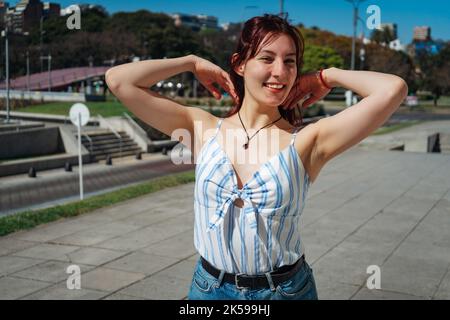 Mittlere Aufnahme einer schönen jungen lateinischen Rothaarigen, die an einem sonnigen Tag lächelt. Stockfoto