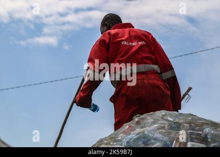 Kisumu, Nyanza, Kenia. 4. Oktober 2022. Ein Mann, der eine Coca-Coca-Firma mit rotem Overall trägt, der mit der Aufschrift „Welt ohne Abfall“ bestickt ist, wird in einem Abfallsammelzentrum für Plastikmüll in Kisumu arbeiten sehen. Aktivisten und Umweltgruppen in Kenia und anderen Teilen der Welt haben die Coca-Cola Company als Sponsor des diesjährigen Klimagipfels COP 27, der im November in Ägypten stattfinden wird, verächtet. (Bild: © James Wakibia/SOPA Images via ZUMA Press Wire) Stockfoto