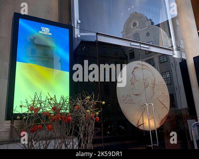 Stockholm, Schweden. 06. Oktober 2022. Auf einer Leinwand vor dem Nobelpreisträger-Museum in Stockholm ist eine ukrainische Flagge mit der Aufschrift „Möge Frieden in dieses Stück unserer schönen Welt kommen“ zu sehen. Am Morgen wird der Gewinner des Friedensnobelpreises bekannt gegeben. Quelle: Steffen TRUMPF/dpa/Alamy Live News Stockfoto