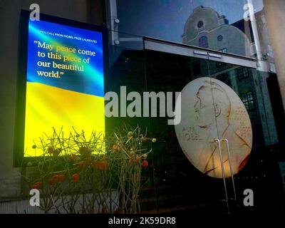 Stockholm, Schweden. 06. Oktober 2022. Auf einer Leinwand vor dem Nobelpreisträger-Museum in Stockholm ist eine ukrainische Flagge mit der Aufschrift „Möge Frieden in dieses Stück unserer schönen Welt kommen“ zu sehen. Am Morgen wird der Gewinner des Friedensnobelpreises bekannt gegeben. Quelle: Steffen TRUMPF/dpa/Alamy Live News Stockfoto