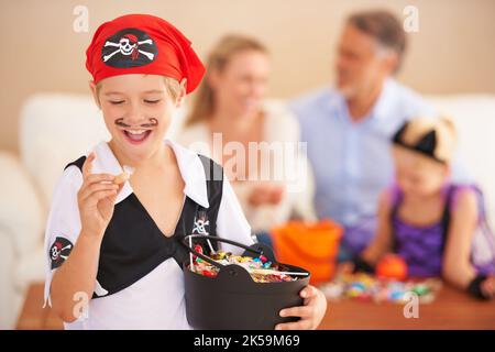 Seine Lieblingsart. Ein kleiner Junge in einem Piratenkostüm gekleidet und hält einen Korb und zum Ausdruck bringen Aufregung über eine süße mit Familie sitzt in der Stockfoto